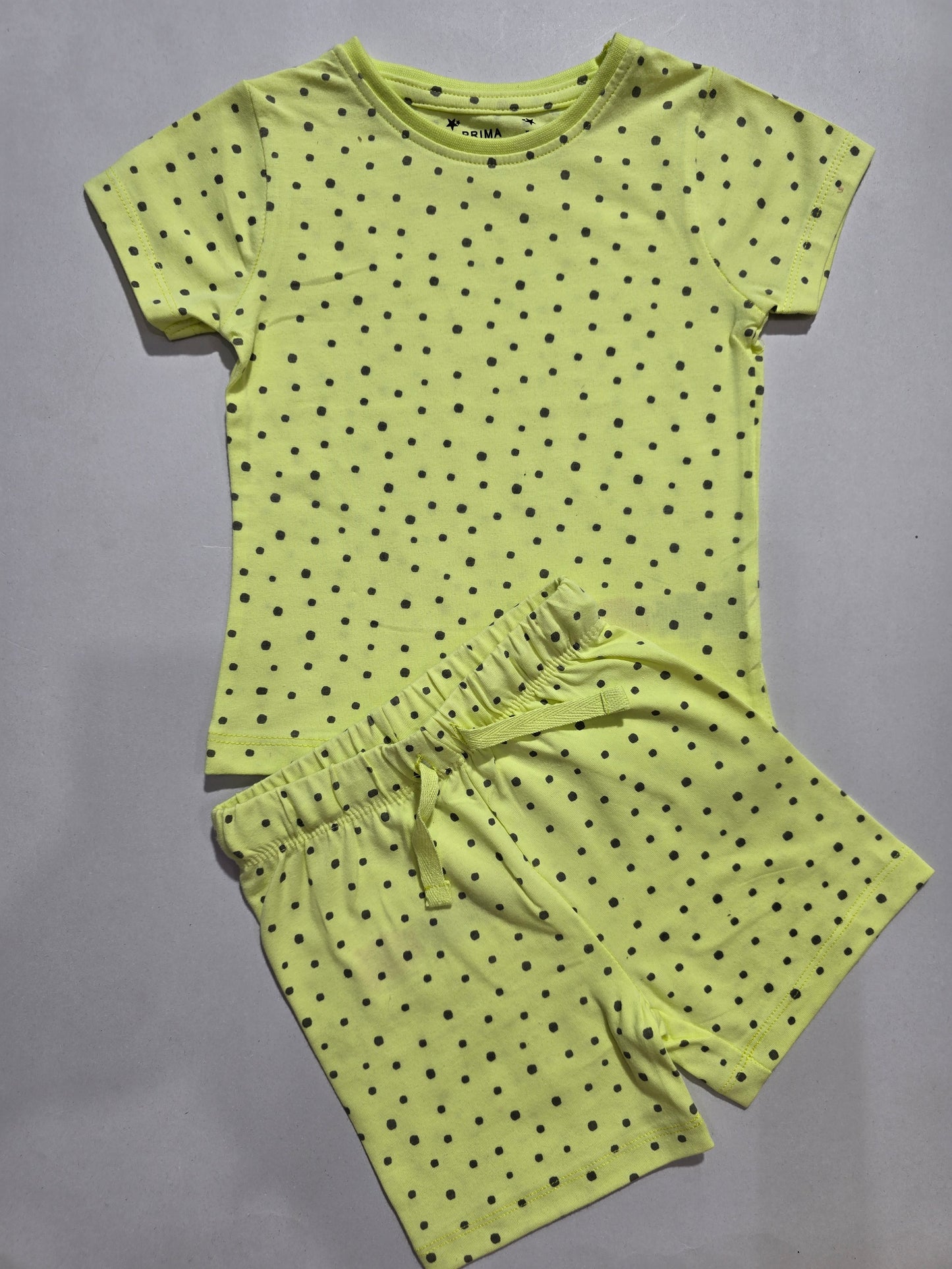 Green polka dot top and shorts set on a gray background
