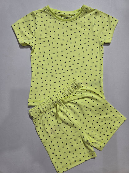 Green polka dot top and shorts set on a gray background