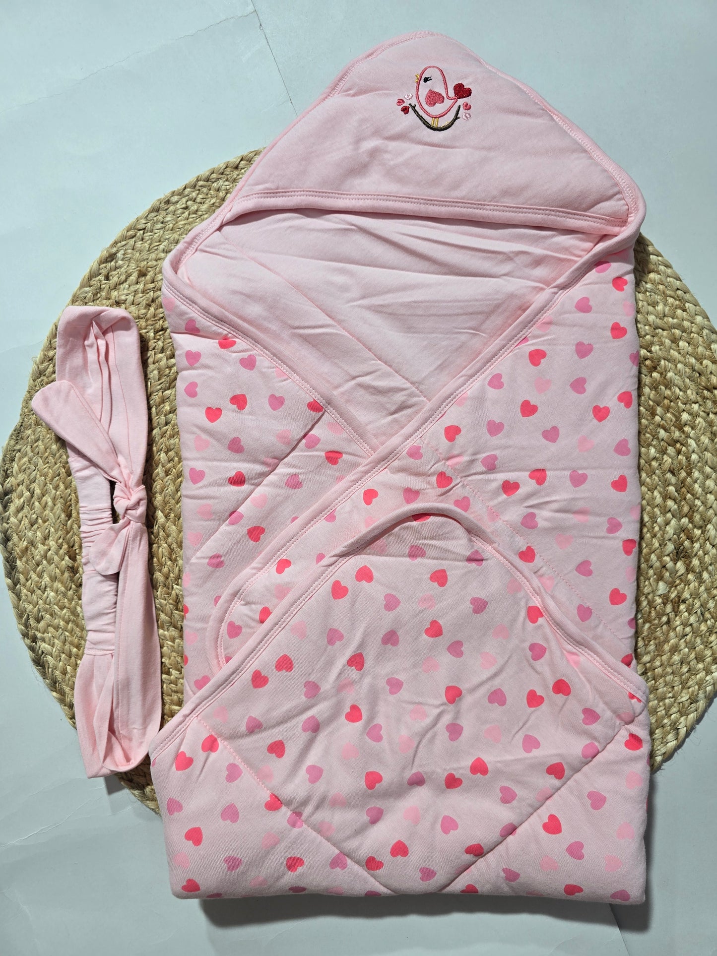 Pink baby wrap with heart pattern on a light blue background