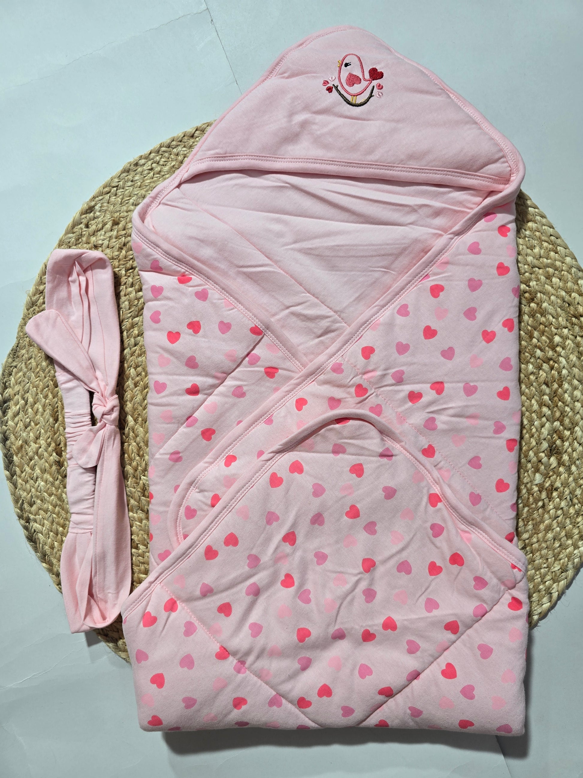 Pink baby wrap with heart pattern on a light blue background